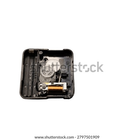 Close-up view of a black quartz clock movement mechanism showing gears, battery compartment, and internal components. Isolated on a white background.