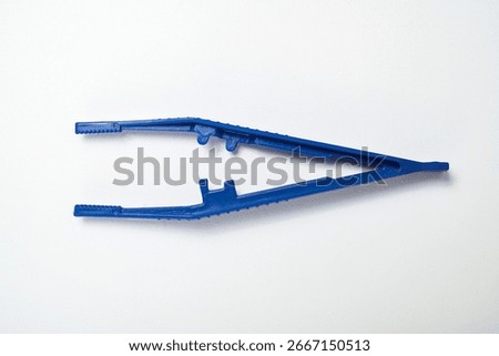 Closeup view of blue plastic forceps or a tweezer tool isolated over a white background