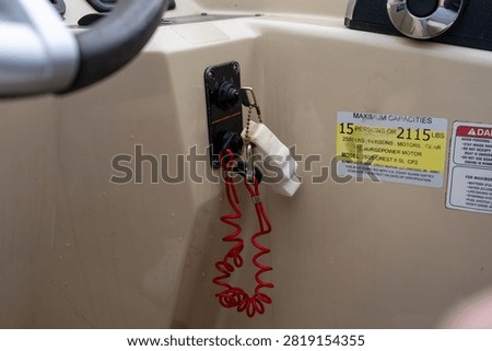 A close-up view of a boat's ignition switch panel showing a red safety lanyard (engine cut-off switch) hanging from the key on the console.