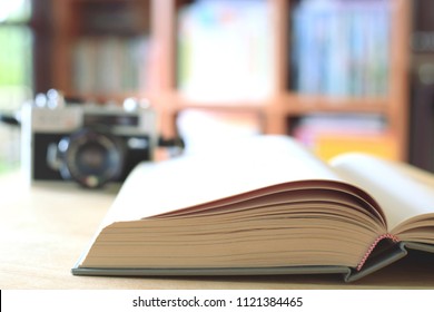 A close-up view of a book open on a table in a library ancient camera is the background selective focus and shallow depth of field