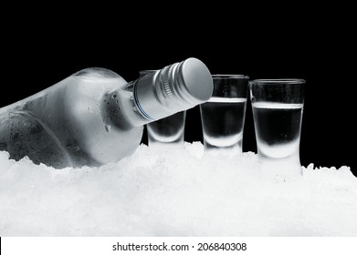 Close-up view of bottle of vodka with glasses standing on ice on black - Shutterstock ID 206840308