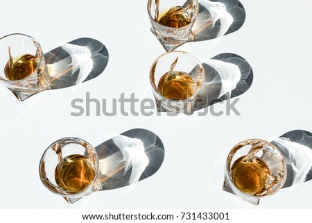 close-up view of bourbon in glasses with shadows on white  