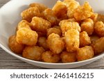 A closeup view of a bowl of deep fried tater tots.