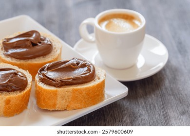 Closeup view of bread with chocolate spread and cup of espresso. Hazelnut bread and coffee. Sweet breakfast.