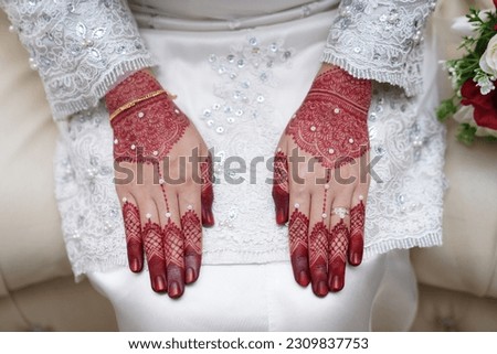 A close-up view of a bride's hands decorated with beautiful henna designs. In Indian culture, Mehndi is a traditional ornamentation essential in Malay wedding traditions.