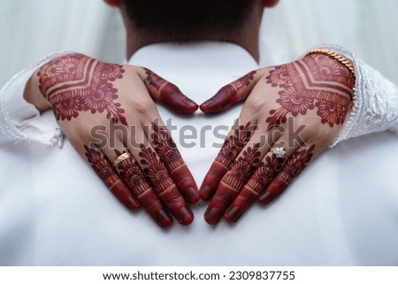 A close-up view of a bride's hands decorated with beautiful henna designs. In Indian culture, Mehndi is a traditional ornamentation essential in Malay wedding traditions.
