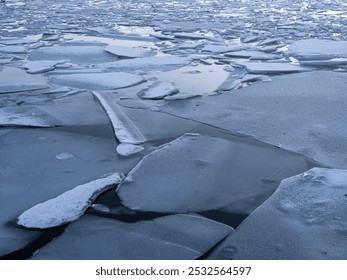 A close-up view of broken ice sheets floating on a body of water, reflecting the cold and serene atmosphere of a winter landscape. - Powered by Shutterstock