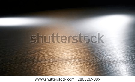 A close-up view of a brushed metallic surface with dramatic streaks of light reflecting across it, creating an abstract and modern aesthetic.