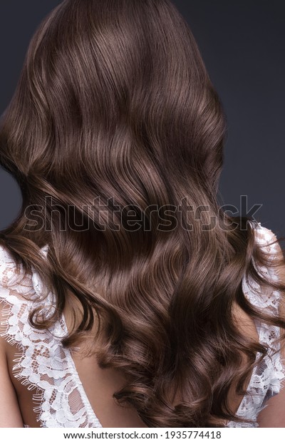 A\
closeup view of a bunch of shiny curls brown\
hair