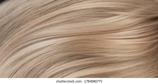 A closeup view of a bunch of shiny straight blond hair in a wavy curved style. - Shutterstock ID 1784080775