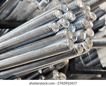 A close-up view of a bundle of long galvanized threaded rods. Metal posts for the construction industry, fasteners.