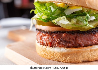 A closeup view of a burger, featuring a burger patty made of plant-based ingredients, in a restaurant or kitchen setting. - Shutterstock ID 1680790648
