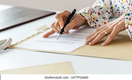 Closeup view of businesswoman proofreading a contract following lines with a pen.