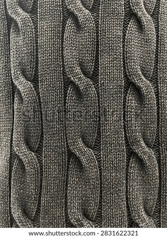 Closeup view of cable knitting patterns. Cable stitch. Black knitted sweater. A swatch of knitted fabric. Fabric pattern, texture and design concept.