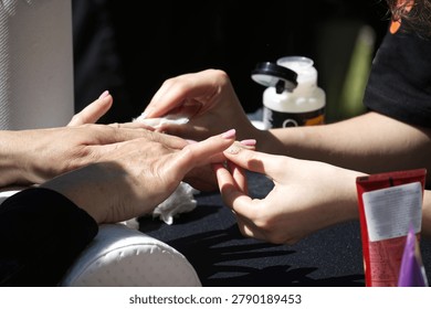 A close-up view captures the detailed process of a nail technician meticulously applying polish, highlighting the artistry and attention to detail involved in creating beautiful nails