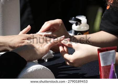 A close-up view captures the detailed process of a nail technician meticulously applying polish, highlighting the artistry and attention to detail involved in creating beautiful nails