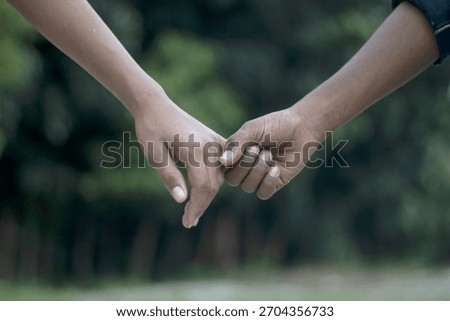 A close-up view captures two hands interlocked, symbolizing a deep bond and mutual reliance. The soft focus background enhances the intimate gesture.