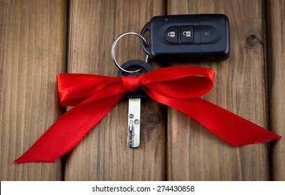 Close-up view of car keys with red bow as present on  wooden background