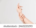 Close-up view of caucasian woman rubbing her wrist using other hand against grey background. Soft focus. Healthcare, cosmetics and self massage theme.