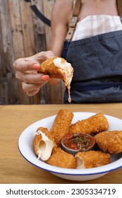 Closeup view of a caucasian woman's hand, dipping a fried mozzarella stick in a red spicy sauce, in the restaurant. - Shutterstock ID 2305334719