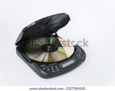 Close-up view of CD player with open lid and golden CD inside isolated on white background.
