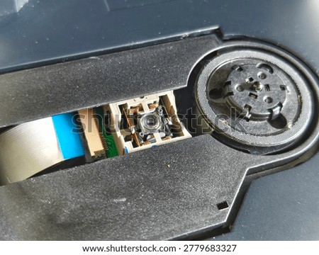 A close-up view of a CD player's internal components, showing the optical laser lens and spindle motor assembly.