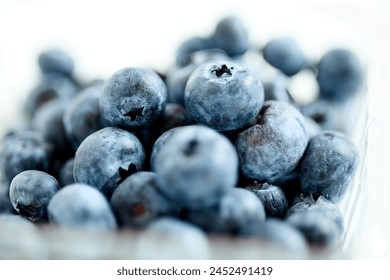 A close-up view of a ceramic bowl filled with fresh blueberries. The plump, deep blue berries are arranged neatly in the bowl, showcasing their vibrant color and juicy texture. - Powered by Shutterstock