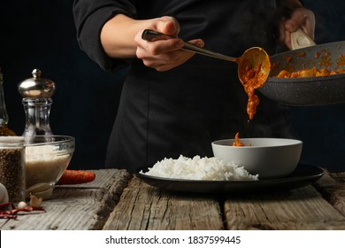 Close-up view of chef pours by ladle chicken curry from pan wok to white bowl. Backstage of serving traditional Indian curry with boiled rice on black background. Frozen motion. - Powered by Shutterstock