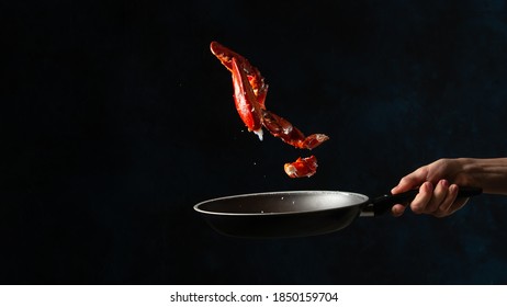 Close-up View Of The Chef Toss Up King Crab Legs Above The Frying Pan On Dark Blue Background. Seafood Concept. Frozen Motion. Backstage Of Preparing Traditional Thai Recipe.