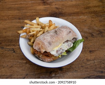 Closeup View Of A Chicken Fried Steak Sandwich With Lettuce, Mayonnaise And French Fries, In A White Bowl On The Wooden Table. 