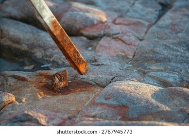 A close-up view of a chisel being used to carve or shape a textured stone surface, showcasing craftsmanship, detailed texture, and the process of stone carving.