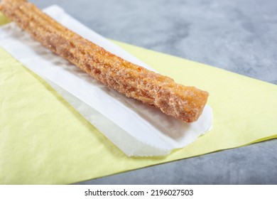 A Closeup View Of A Churro On A Paper Liner.