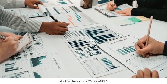 Close-up view of a collaborative team engaging in data analysis with charts and graphs, showcasing teamwork and strategic planning in an office environment. SACTR