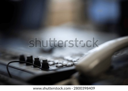 A close-up view of a communication device and control panel with numerous buttons, switches, and adjustable knobs, commonly found in an operational workstation or broadcasting environment