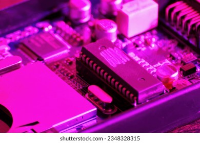 Closeup view of complex modern pcb with processor in the pink neon light. Cloud technologies and computer science and engineering