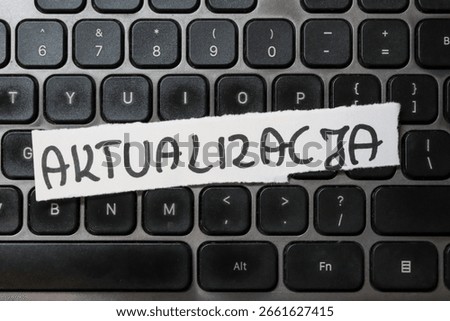A close-up view of a computer keyboard featuring a handwritten note that reads ACTUALIZATION. This image symbolizes technology, updates, and digital communication.