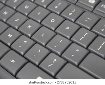 Close-up view of a computer keyboard showing punctuation keys and letter buttons, highlighting modern technology and typing tools.