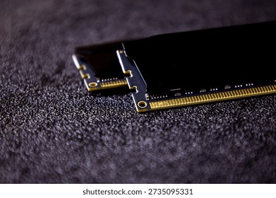 Close-up view of computer memory modules placed on a dark textured surface showing details of electronic components and connectors