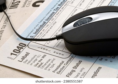 A close-up view of a computer mouse with a 1040 form on top of tax instructions.