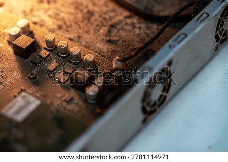 Close-up view of a computer power supply unit showing circuit board, capacitors, cooling fans, and electrical components within the metal casing, emphasizing technology and hardware design.