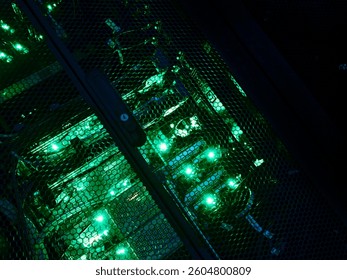 A close-up view of a computer server rack featuring vibrant green illumination, showcasing advanced technology and intricate wiring in a data center environment.