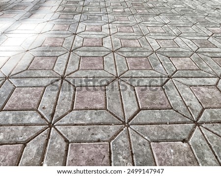A close-up view of concrete pavement surface, showcasing interlocking pavers arranged in a diagonal pattern