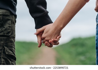 close-up view of couple holding hands, young beautiful caucasian man and woman take each other hands, walking on pathway in park in summer, love and family concept, selective focus - Powered by Shutterstock