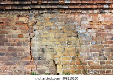 Close-up view of cracked old building brick wall with eroded bricks on top, background concept