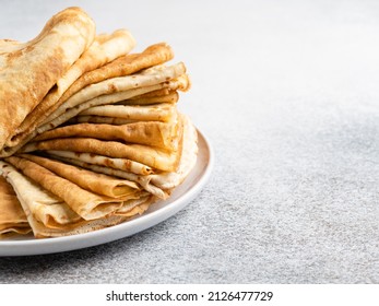 Closeup view of crepes pile. Stack (heap) of thin pancakes, traditional russian blini on ceramic plate. Tasty healthy breakfast or dessert. Maslenitsa or pancakes week concept. Copy space. 