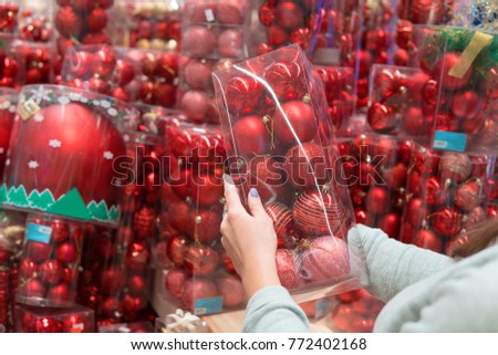 closeup view of customer girl hands taking red Christmas tree decoration balls.