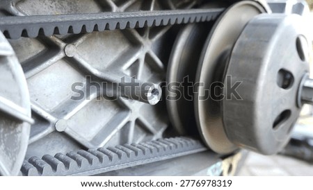 Close-up view of the CVT (Continuously Variable Transmission) housing on an automatic motorcycle being disassembled with the van belt or v belt still attached in a circular fashion