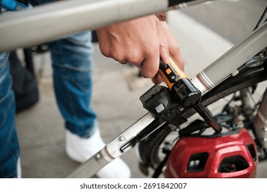 Close-up view of cyclist's hands securing a bicycle to a rack with a u-lock, highlighting the importance of safety and security in a bustling urban environment
