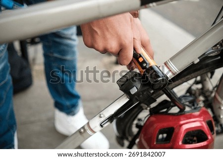 Close-up view of cyclist's hands securing a bicycle to a rack with a u-lock, highlighting the importance of safety and security in a bustling urban environment