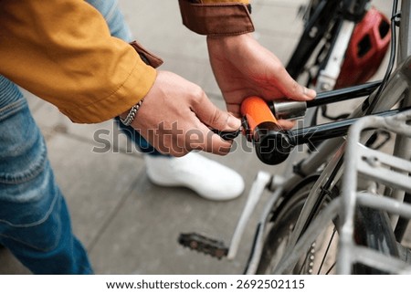 Close-up view of cyclist's hands securing a bicycle to a rack on a bustling city street, emphasizing the importance of safety and protection against theft while commuting